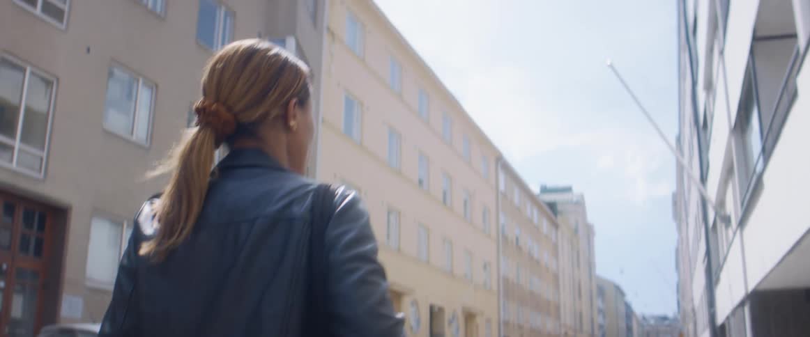 A woman keeps looking behind herself as she walks down a city street