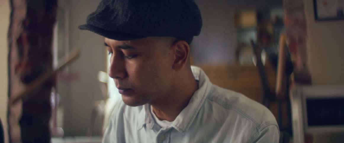 A man sits in a restaurant and eats and drinks as employee cleans tables in the background