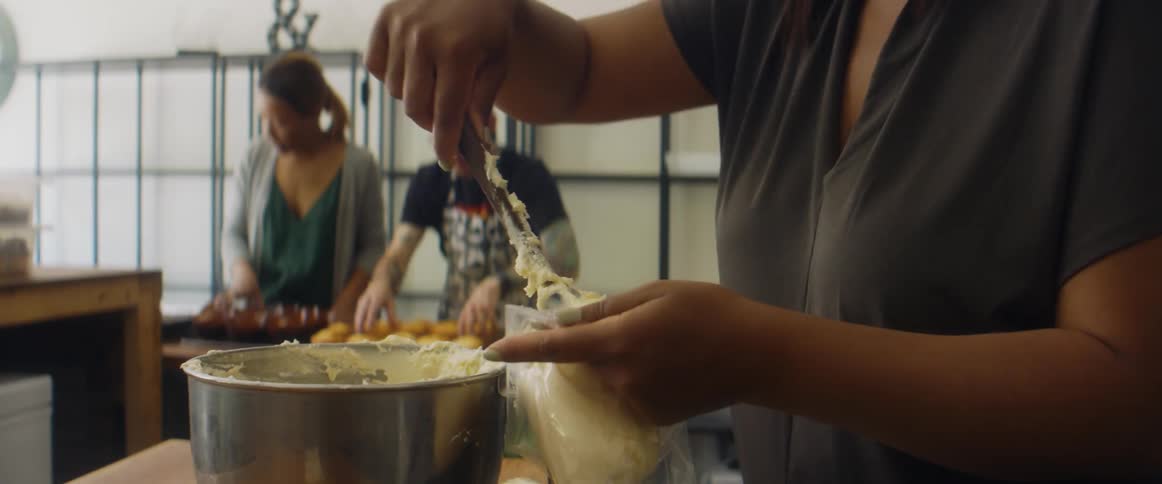 Workers mixing cream in a bowl sweets in a bakery with coworkers