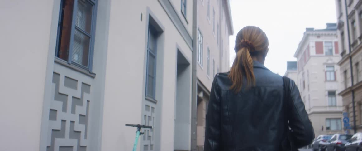 A woman walking down a sidewalk in a city