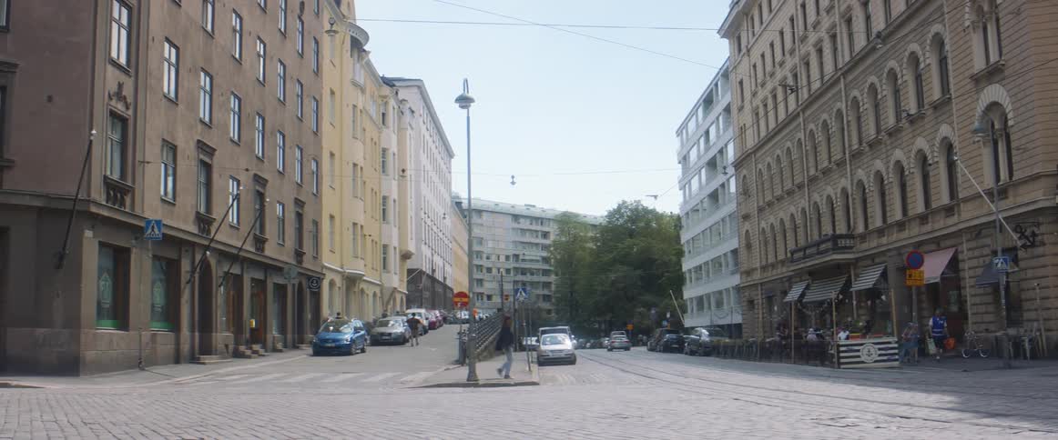 Pedestrians walking on a city street with vehicles buildings the sky and clouds in the background