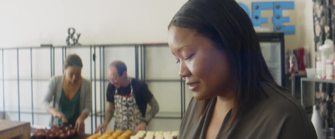 Three bakers preparing cupcakes and baked goods in a cafe
