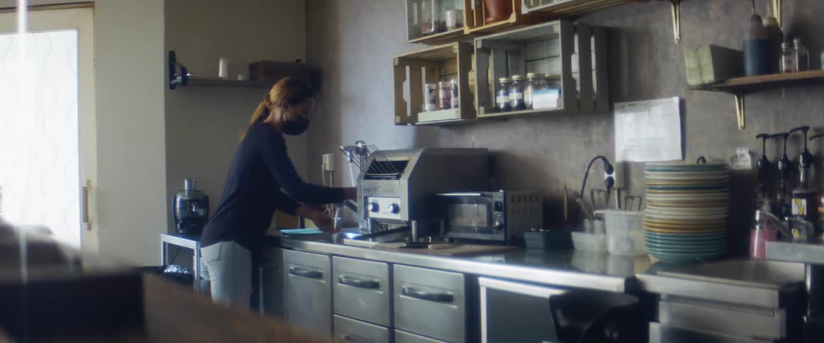Woman wearing a black face mask washes her hands on the kitchen sink