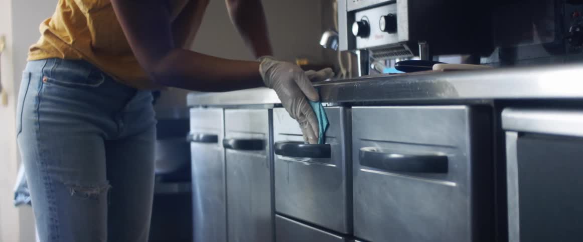 A person in a room with gloves using a sponge to clean drawers