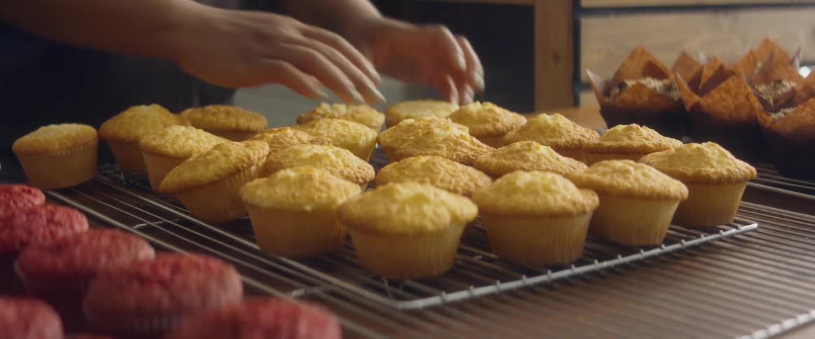A person is aranging muffins in the bakery