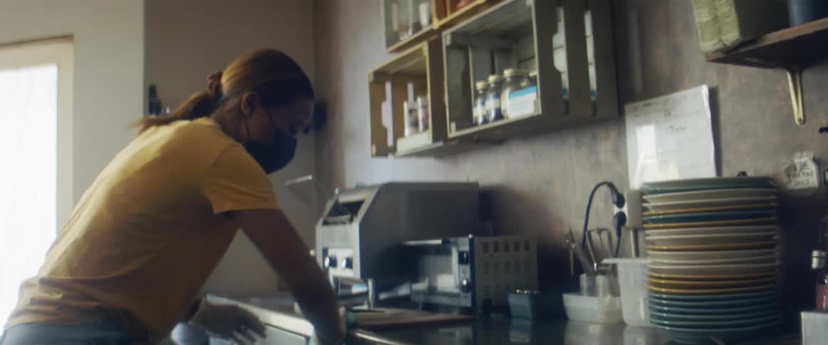 A woman is cleaning the kitchen with a rag