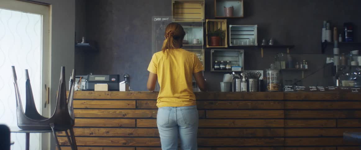 A woman is standing at a counter and places a menu board on it