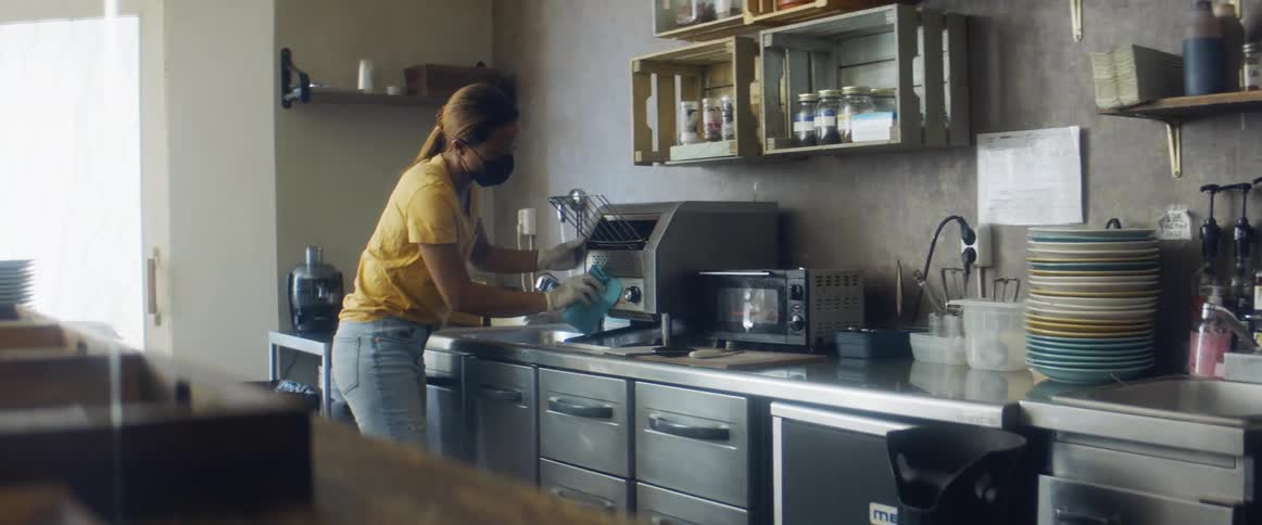 A cafe employee cleans the equipment with a towel