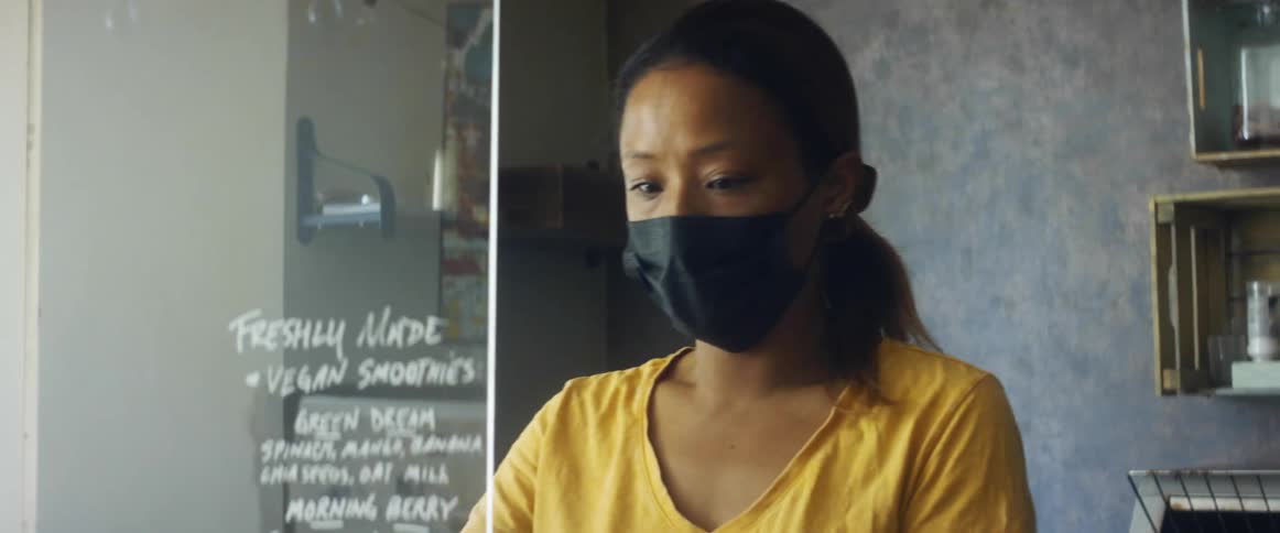 A woman carries a plastic barrier and places it on the counter in a cafe