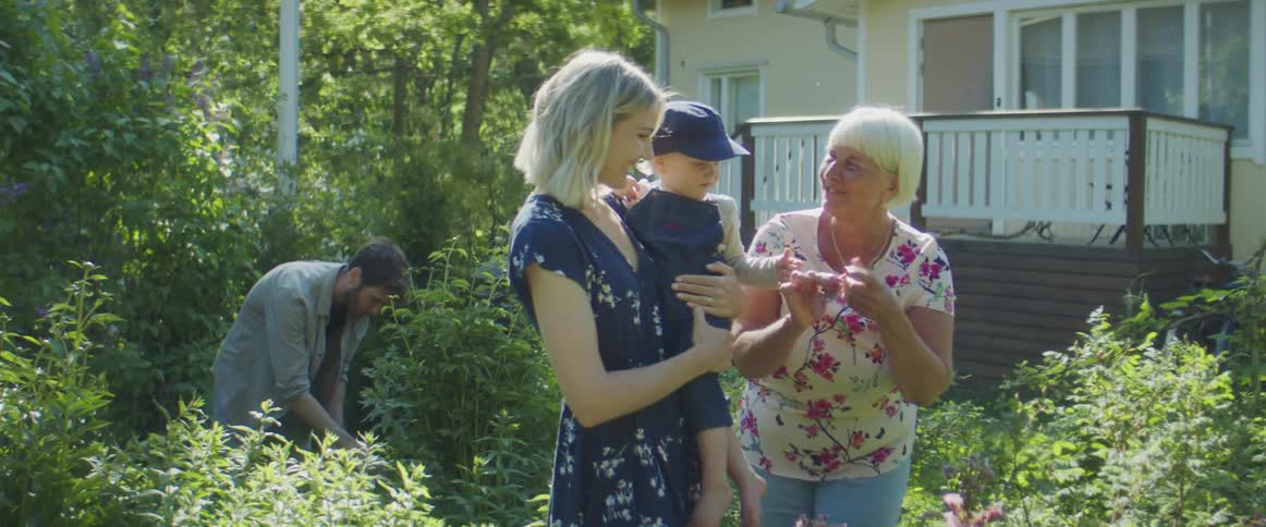 Grandmother playing with her grandson picks up flowers from the garde in the backyard