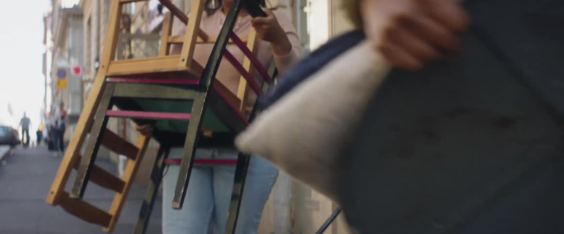 Three women next to a building on a city street moving tables and chairs
