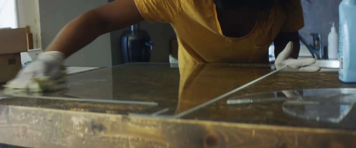 A woman wearing a mask cleans and disinfects a counter in a coffee shop