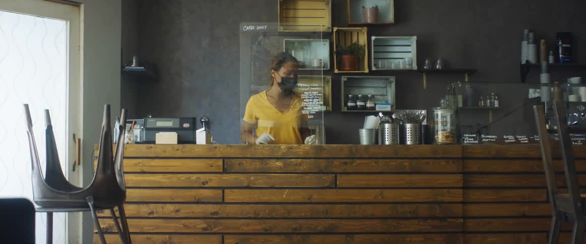 A woman wearing gloves places a menu board on a counter
