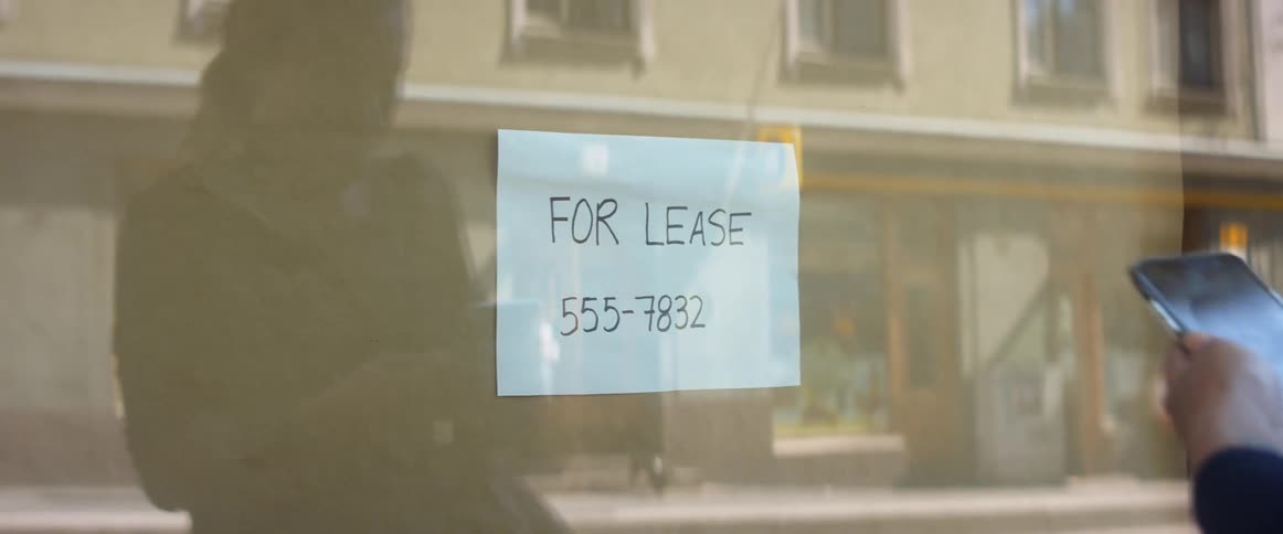 A woman taking out a smartphone to take a photo of a sign on a building