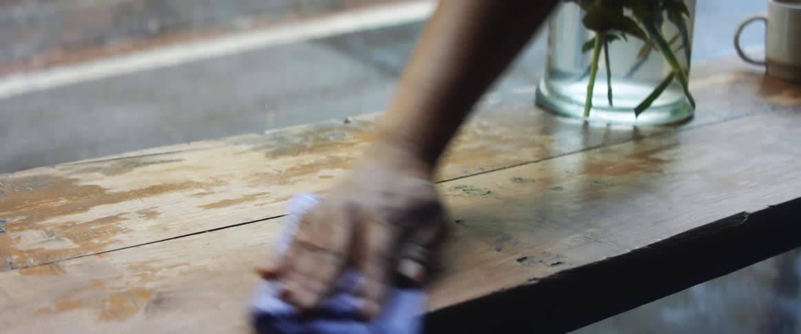 An employee in a coffee shop picks up empty plate and glass to clean the table