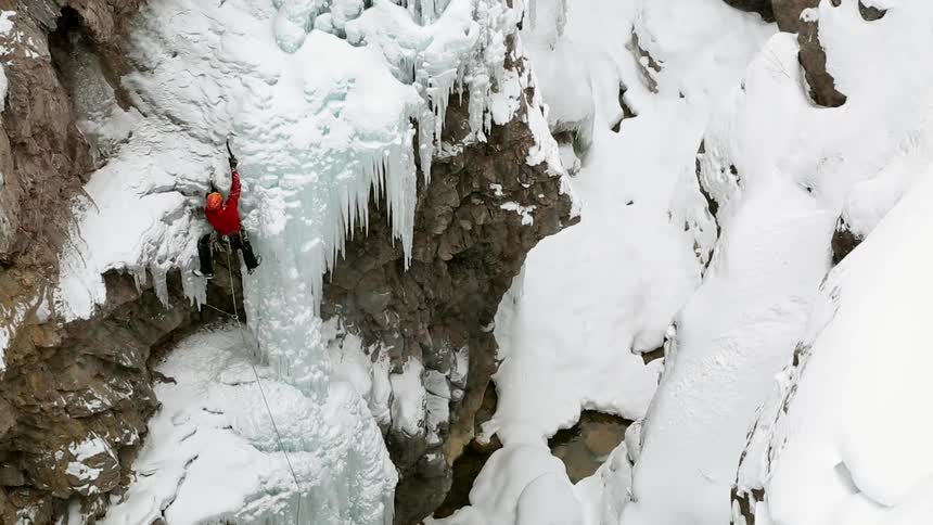 Mountain climber using his pick to chip away at the ice