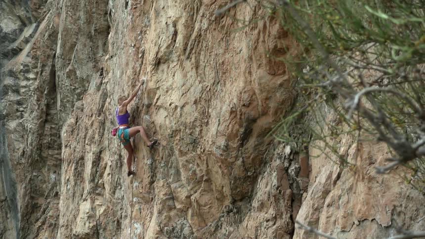Woman climbing a cliff wall