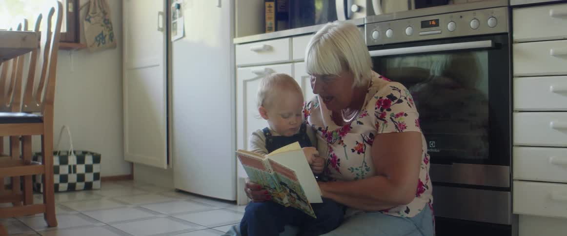 A grandmother reads a book to her grandson