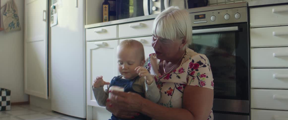Grandmother playing with her grandson on the kitchen floor at home