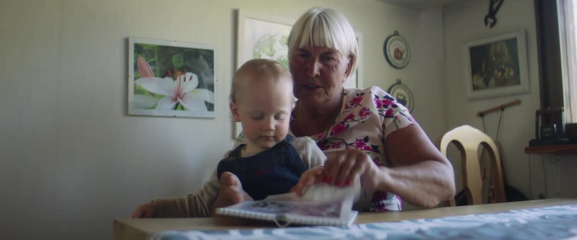 A grandmother is sitting with her grandson reading a paper