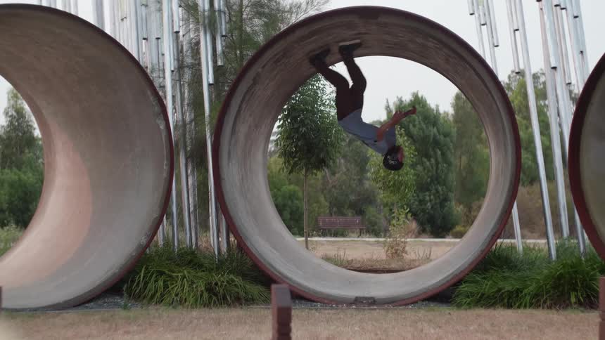 Inline skater wearing helmet performs loop in large concrete tube segment