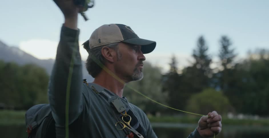 A man on the shore casts his fishing rod in to the water