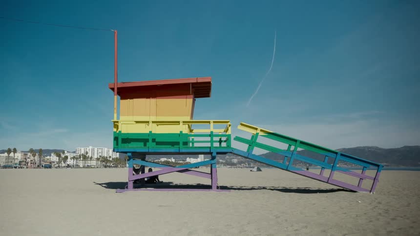 A lifeguard tower on the beach is painted in rainbow colors