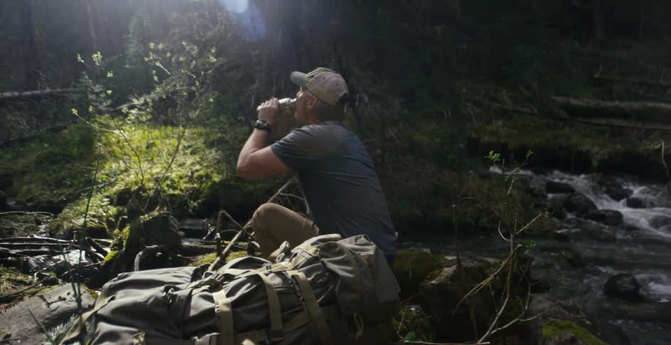 Person drinking water by creek