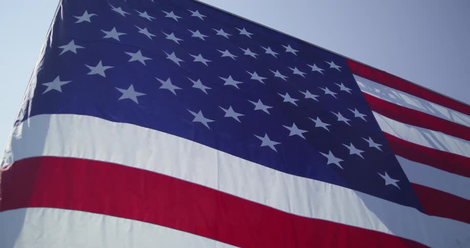 An american flag ripples in the wind as the sun shines brightly upon it