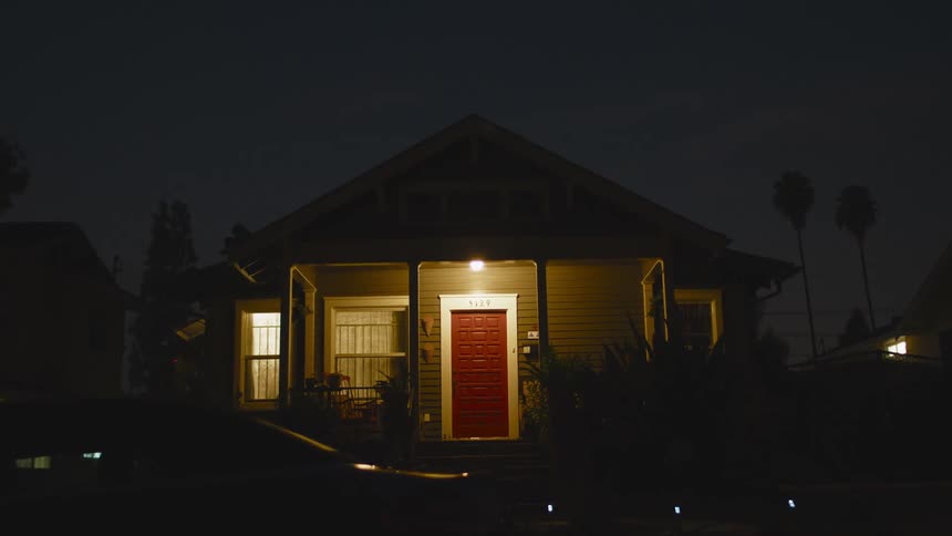 Light on the porch of a small house in a neighborhood at night