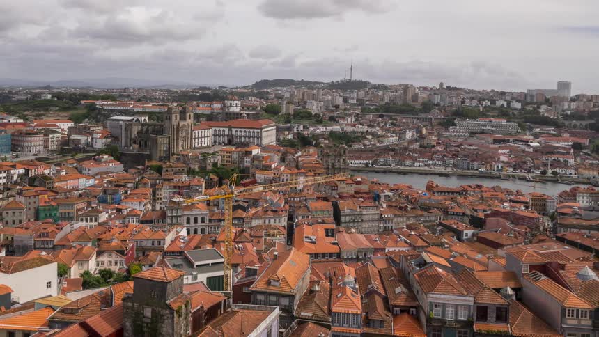 Boats travel on a river cutting through a city with orange roof topped buildings