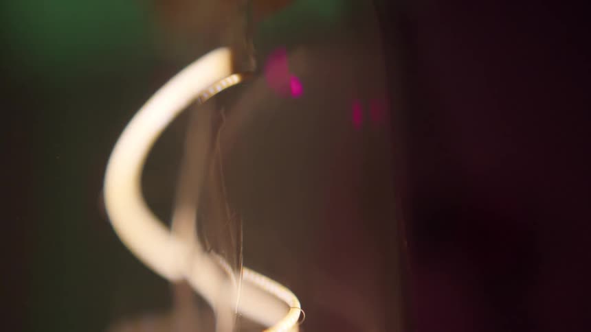 A curving filament glows and shines with colorful lights behind