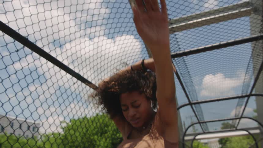 Woman performs dance moves on a walkway on a bridge under a blue sky