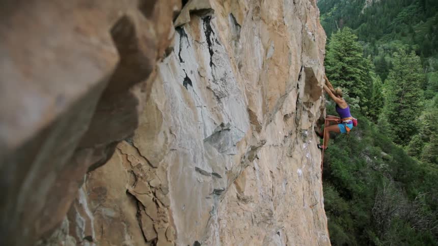 A woman is rock climbing on a tall cliff
