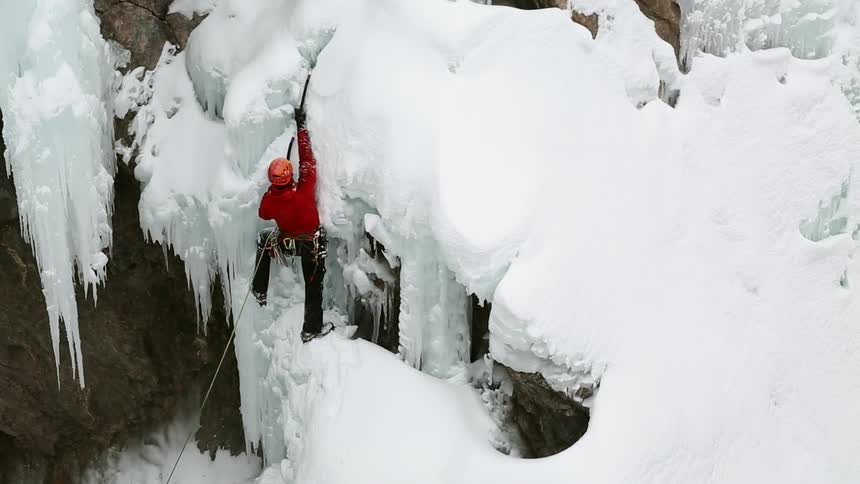 A person in red climbs a snow mountain