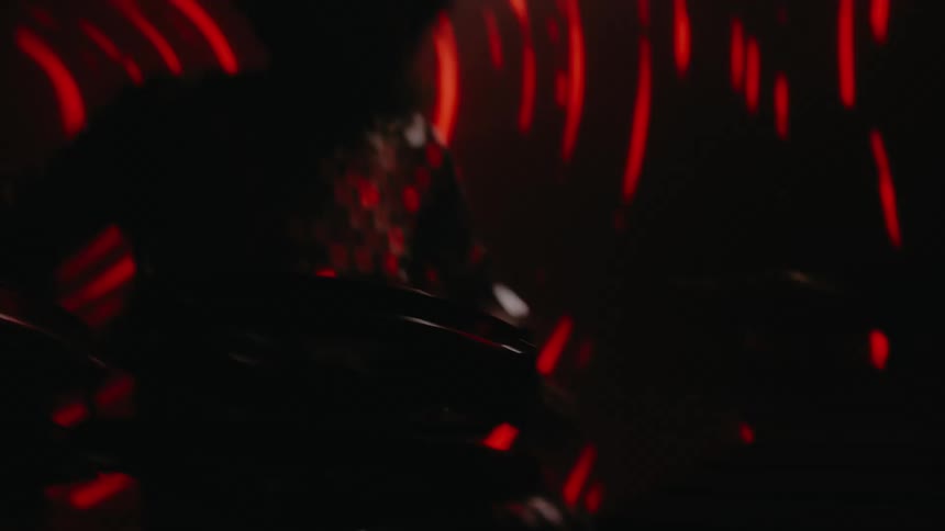A man in a room playing drums with drumsticks with a screen in the background