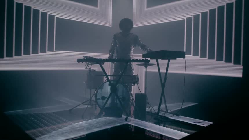 A percussionist is playing multiple musical instruments with lights flashing around him
