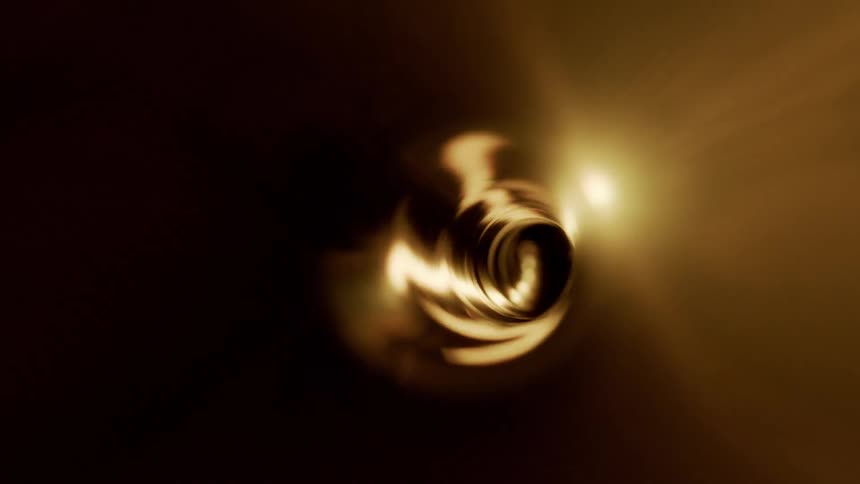 Swirling liquid creates vortex as nearby light colors it partly gold and partly black