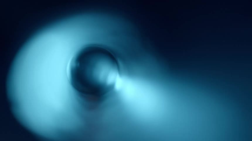 Blue spinning vortex moves against black background