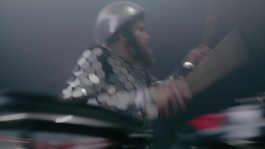 Drummer wears outfit with small shiny plates as he plays drums on fog stage