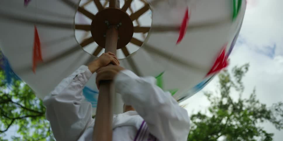 Man spins an ornamental umbrella that is on top of a pole