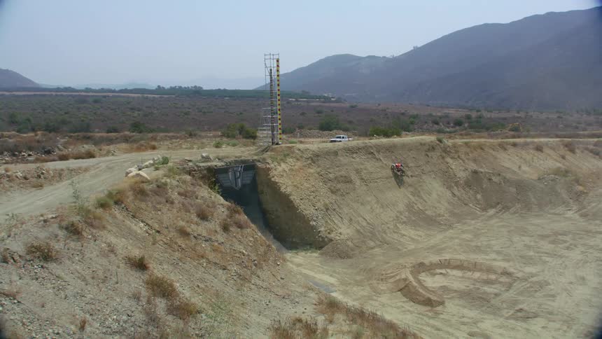 A bicyclist rides through an empty quarry and flips through the air