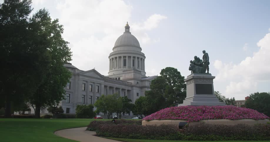 A statue in front of a government building with a few cars in the parking lot