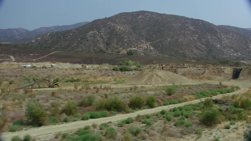Rider on a dirt bike rides up a ramp and soars through the air and lands safely in the desert