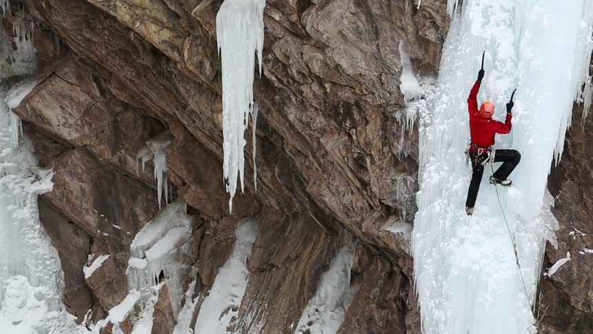 A person is climbing ice on a cliff