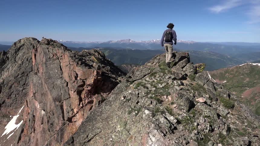 A hiker climbs to the peak of a mountain