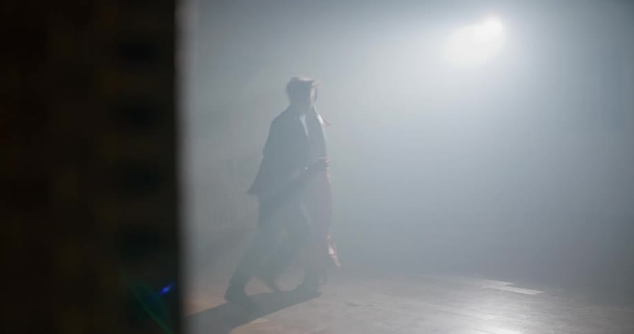 Young couple dancing inside a room filled with smoke under a spotlight