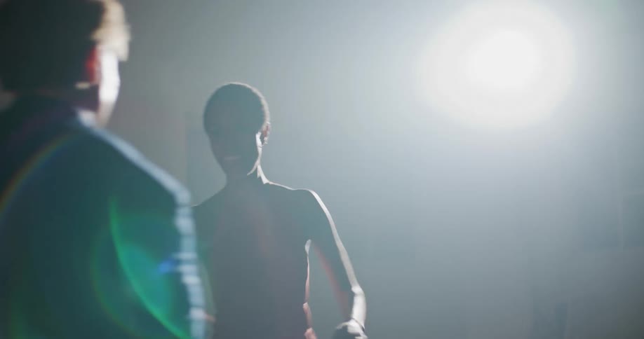 A man and a woman in a room dancing with a spotlight and a wall in the background