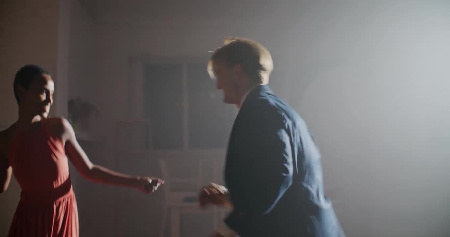 Couple smile as they dance in dimly lit room