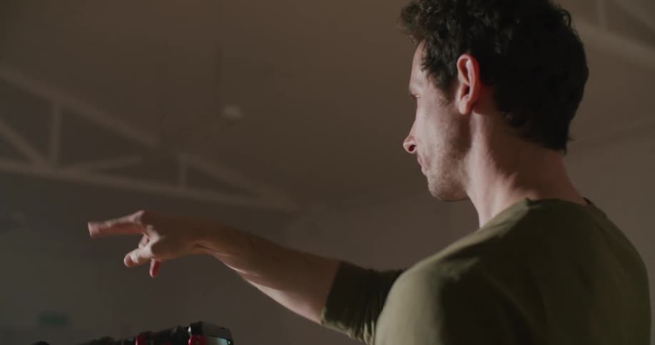Filmmaker holding a camera directing actors inside a warehouse